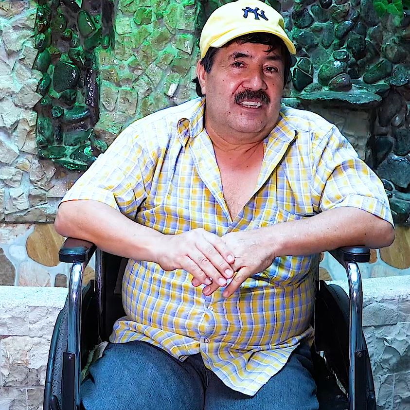 Hombre de Ecuador con gorra sentado en silla de ruedas