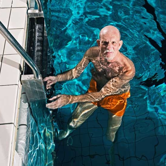 Persona mayor en la escalera de la piscina