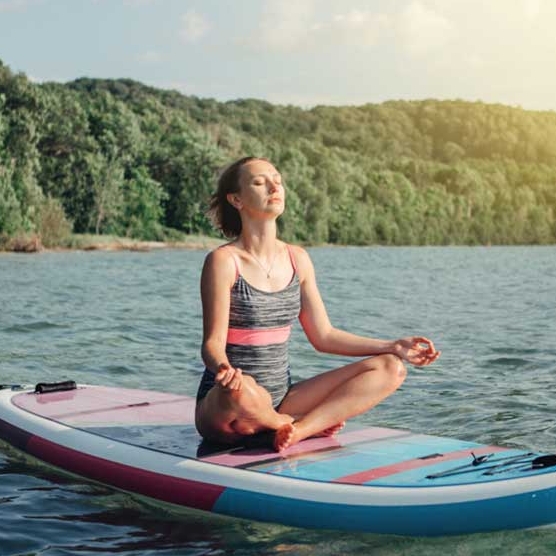 mujer joven meditando en una tabla de raquetas de pie