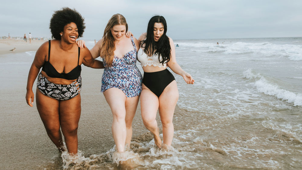 Tres jóvenes en la playa, pies en el agua: Me gusta pasar tiempo con mis amigos en la playa.