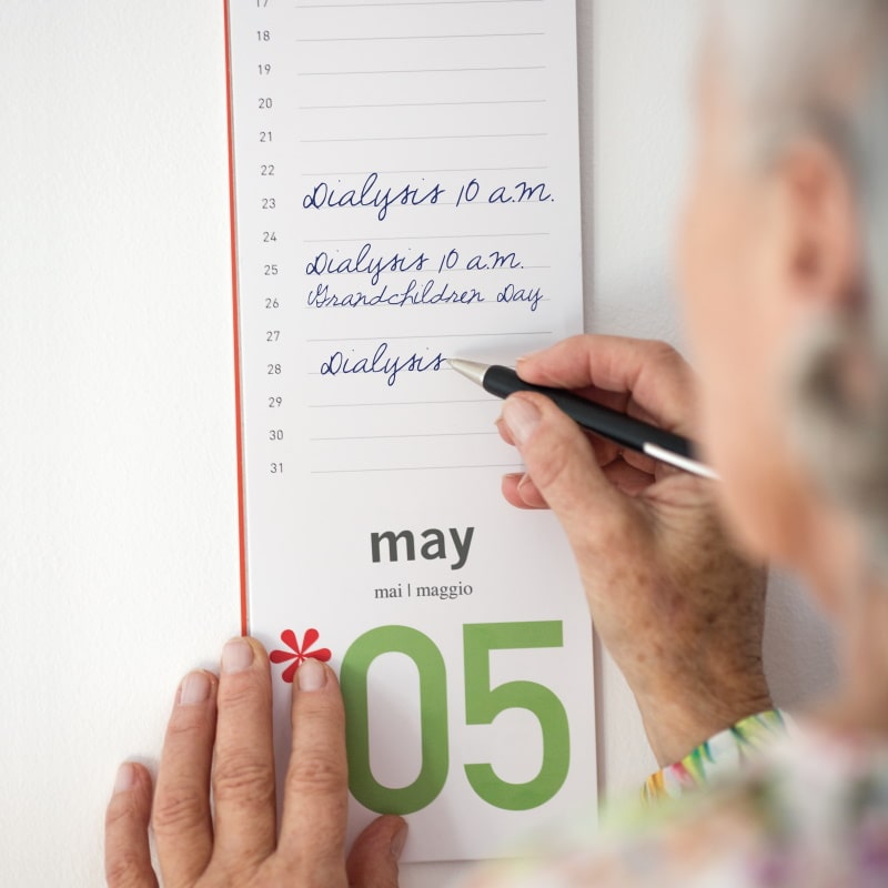 Una mujer mayor toma notas en su calendario