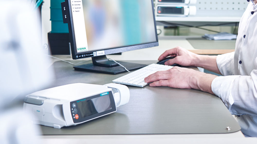 Alguien está sentado delante de un ordenador, también hay una bomba espacial en el escritorio