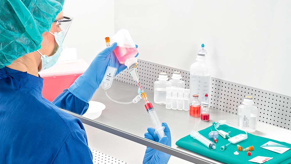 Una farmacéutica extrae la jeringa bajo el flujo de aire laminar