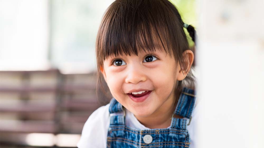 Un niño alegre mira hacia arriba, su sonrisa irradia felicidad e inocencia. 