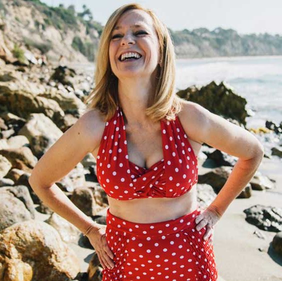 mujer en la playa, risa con bikini rojo con puntos blancos